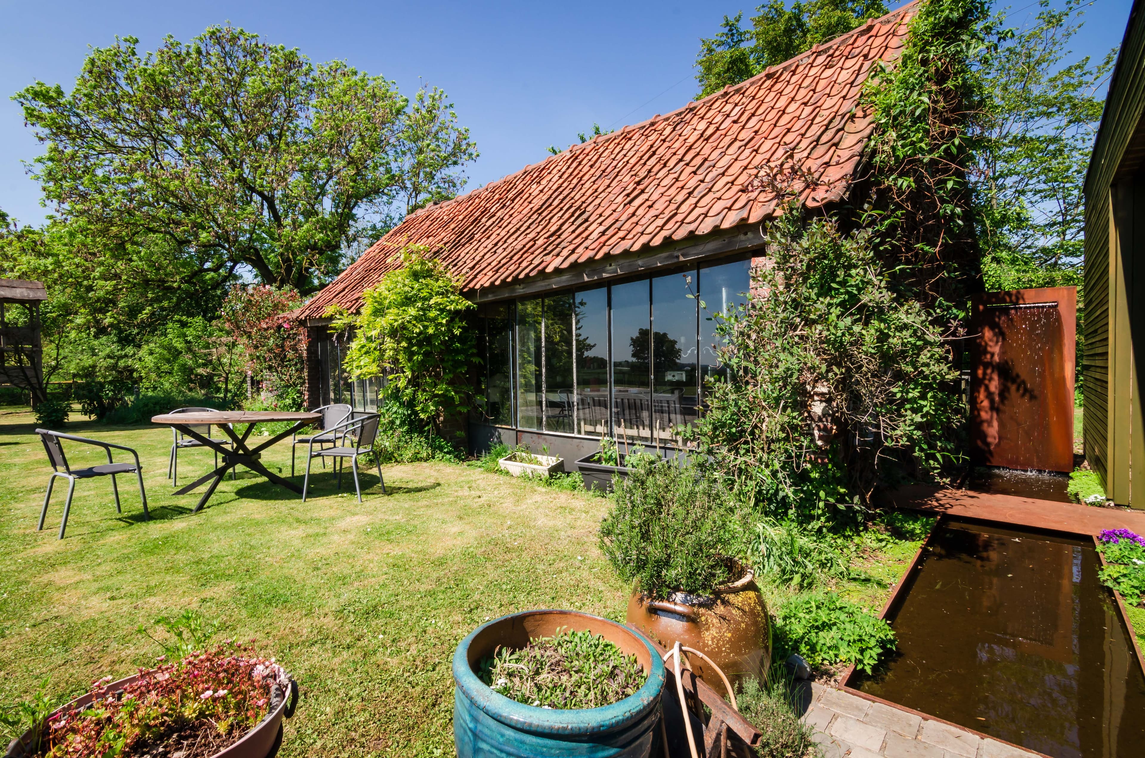 extérieur d'une grange rénovée avec jardin et bassin