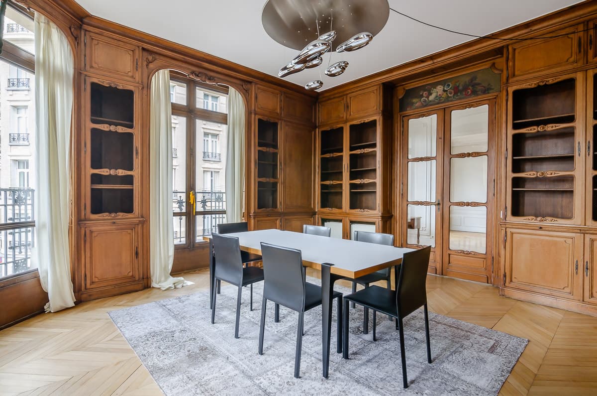 salle à manger habillée de boiseries anciennes avec bibliothèques vitrées