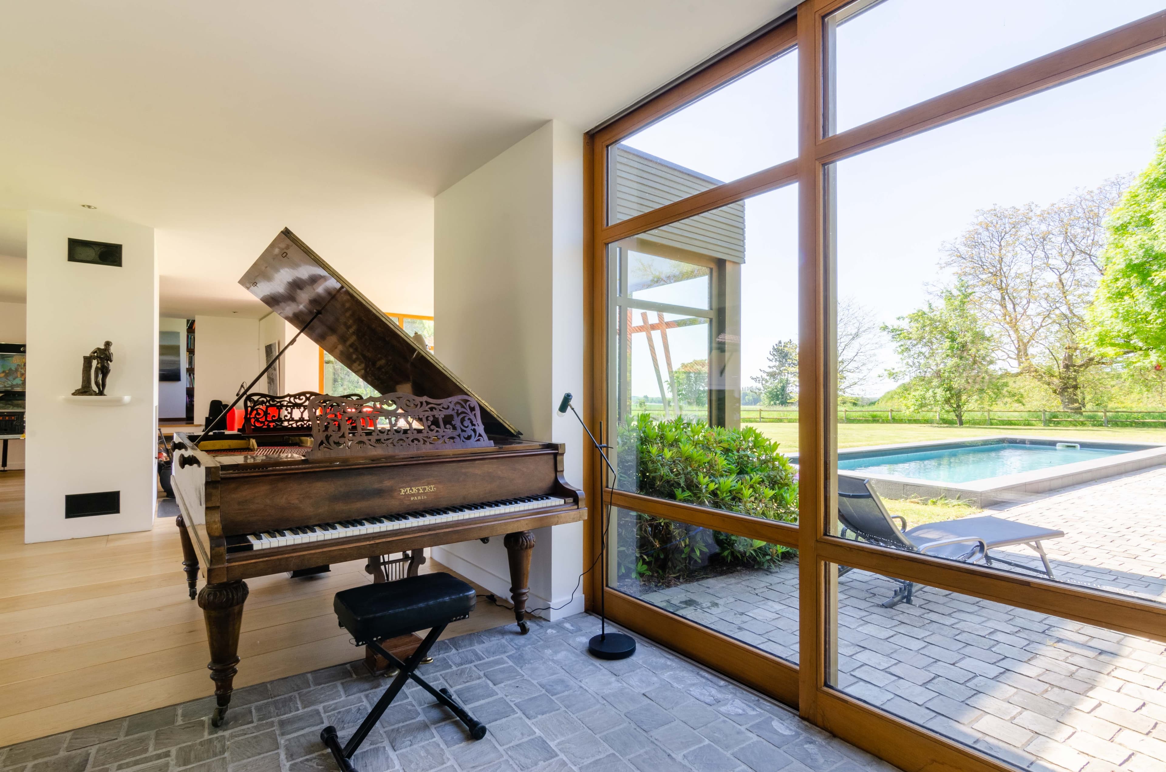salon avec piano à queue face à la piscine